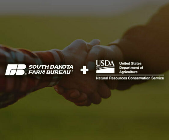 Two men shake hands in a field. The South Dakota Farm Bureau and the NRCS logo overlay the image.